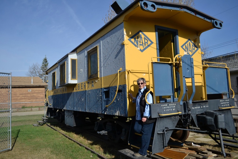 Photo by Carl BR Johnson -- Colleen Groat, Pouce Coupe museum curator, stands on the steps, of the caboose. The restoration project needs a $20,000 infusion for a paint job and structural restoration.