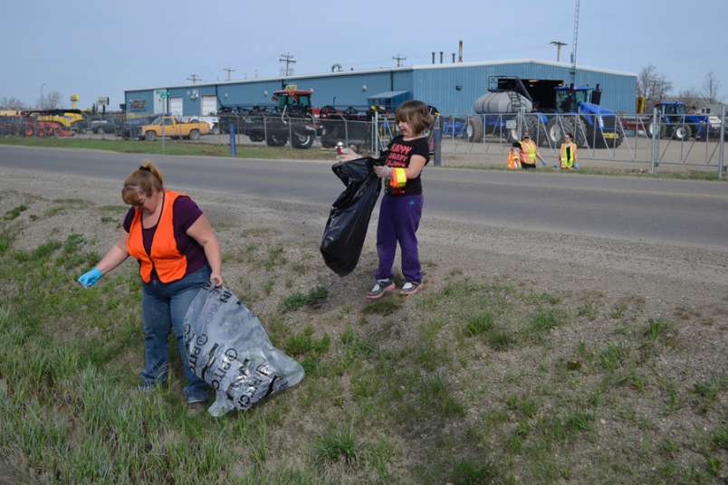 Photo by Carl BR Johnson -- Clarise Handfield, and her daughter Cassidy, clean up 116th Avenue, East of 8th Street. They're volunteering for the City of Dawson Creek in this annual spring garbage cleanup along with an army of other across the city.