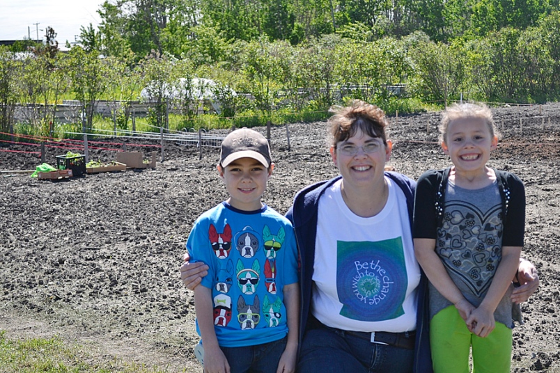 Photo by Carl BR Johnson -- Teacher Karen Fraser, and students, Makenna Aven and Ethan Halberson, were getting dirty at the community gardens planting pumpkins and peas.